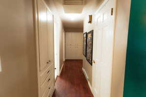Hallway with dark wood-type flooring and baseboards