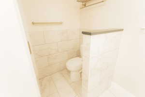 Bathroom featuring toilet, tile walls, and tile patterned flooring