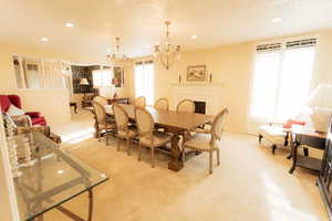 Dining area with a chandelier, light colored carpet, recessed lighting, and baseboards