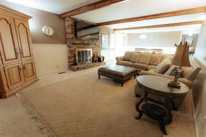 Living area featuring a brick fireplace, wainscoting, and light colored carpet