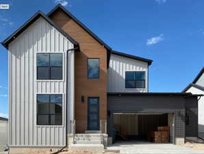 View of front of home with board and batten siding, concrete driveway, and a garage