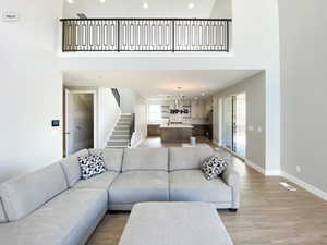 Living area with healthy amount of natural light, a towering ceiling, stairway, recessed lighting, and baseboards