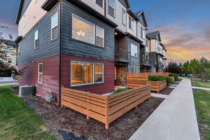 View of property exterior with a vegetable garden, cooling unit, a residential view, and stone siding