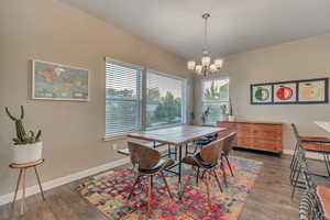 Dining space with a chandelier, wood finished floors, and baseboards