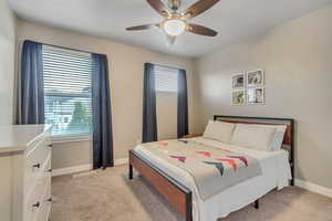 Bedroom featuring multiple windows, light colored carpet, baseboards, and a ceiling fan