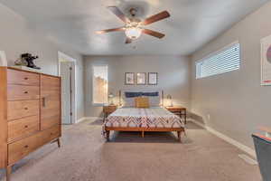 Bedroom with light carpet, baseboards, and ceiling fan