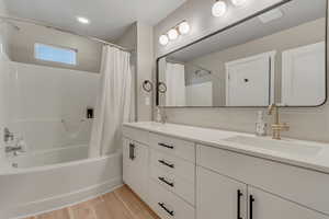 Full bathroom featuring shower / tub combo, double vanity, and wood finished floors