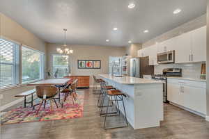 Kitchen featuring stainless steel appliances, a sink, light countertops, a breakfast bar, and recessed lighting