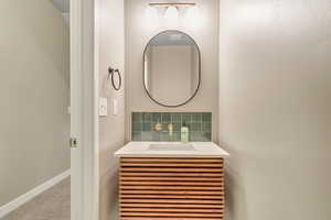 Bathroom with vanity, baseboards, and tasteful backsplash
