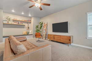 Living area featuring carpet, a ceiling fan, baseboards, and healthy amount of natural light