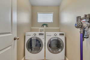Washroom with washing machine and clothes dryer and baseboards