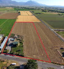 Aerial view of sparsely populated area with rows of crops, property boundaries highlighted, and a mountainous background