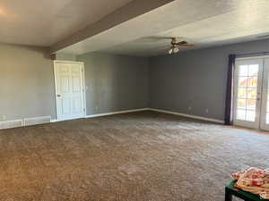 Carpeted empty room featuring a ceiling fan and baseboards