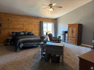 Bedroom featuring carpet, lofted ceiling, a textured ceiling, ceiling fan, and wooden walls
