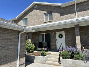 Doorway to property with a porch and brick siding