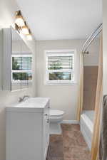 Bathroom with vanity, toilet, shower / bath combo, and baseboards