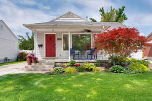View of front facade with covered porch, a front yard, a ceiling fan, and roof with shingles