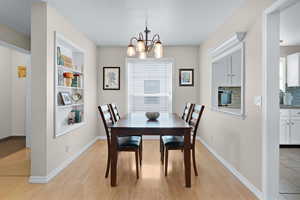 Dining area featuring a chandelier, light wood finished floors, built in features, and baseboards