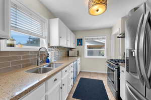 Kitchen featuring stainless steel appliances, a sink, tasteful backsplash, and healthy amount of natural light