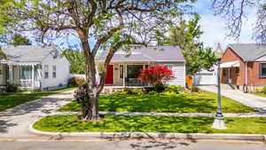 View of front facade with a porch, a front yard, concrete driveway, an outbuilding, and a detached garage