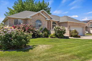 View of front facade featuring brick siding, an attached garage, a front yard, and roof with shingles