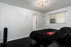Bedroom featuring a textured ceiling, baseboards, and wood finished floors