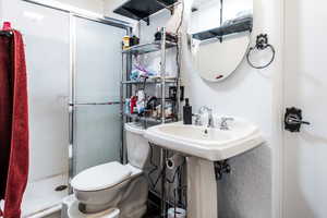 Full bath with a shower stall, toilet, and a textured wall
