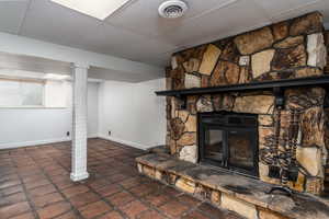 Basement featuring a drop ceiling, baseboards, and a stone fireplace