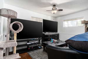 Living room featuring a ceiling fan, wood finished floors, and a wainscoted wall