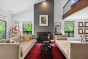 Living room featuring a fireplace, plenty of natural light, and high vaulted ceiling