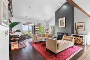 Living room with lofted ceiling, hardwood / wood-style floors, a fireplace, and recessed lighting