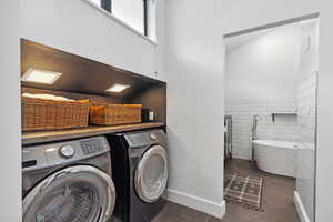 Laundry room with washer and dryer, tile patterned flooring, tile walls, and a wainscoted wall