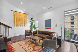 Living room with wood-type flooring, vaulted ceiling, recessed lighting, and baseboards