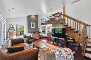 Living area featuring stairs, a towering ceiling, wood finished floors, and recessed lighting