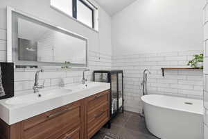 Bathroom with tile walls, double vanity, a soaking tub, tile patterned floors, and wainscoting