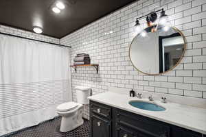 Full bath featuring tile walls, vanity, toilet, tile patterned floors, and curtained shower