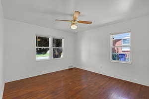 Unfurnished room with dark wood finished floors, baseboards, and a ceiling fan