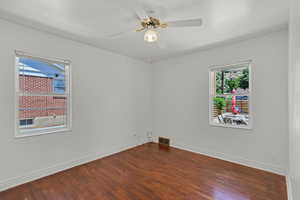 Unfurnished room featuring dark wood finished floors, baseboards, and ceiling fan