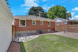 Rear view of house featuring brick siding, a chimney, a patio area, and roof with shingles