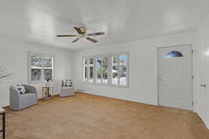 Foyer entrance featuring light colored carpet, plenty of natural light, and a ceiling fan