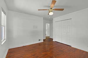 Unfurnished bedroom featuring wood finished floors, baseboards, a closet, and ceiling fan