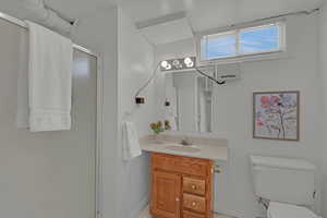 Full bath with a stall shower, vanity, toilet, and baseboards