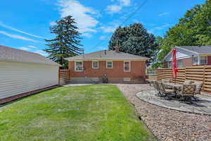 Back of property featuring brick siding, a chimney, and a patio area