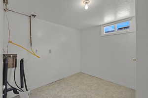 Basement featuring a textured ceiling and baseboards