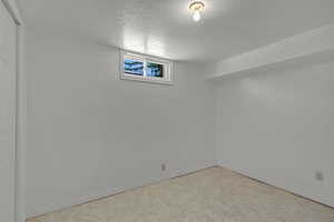 Basement with a textured ceiling, baseboards, and carpet flooring