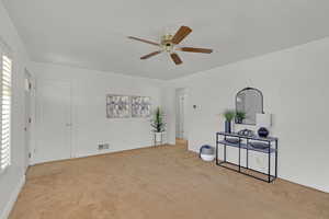 Unfurnished living room featuring light colored carpet, ceiling fan, and baseboards