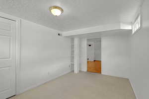 Carpeted empty room with a textured ceiling and baseboards