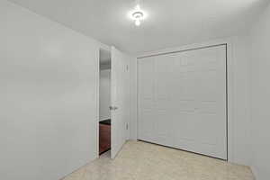 Unfurnished bedroom featuring a textured ceiling, baseboards, and a closet