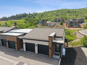 Contemporary home featuring a view of trees and a shingled roof
