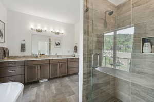Full bath with a shower stall, vanity, and a freestanding bath